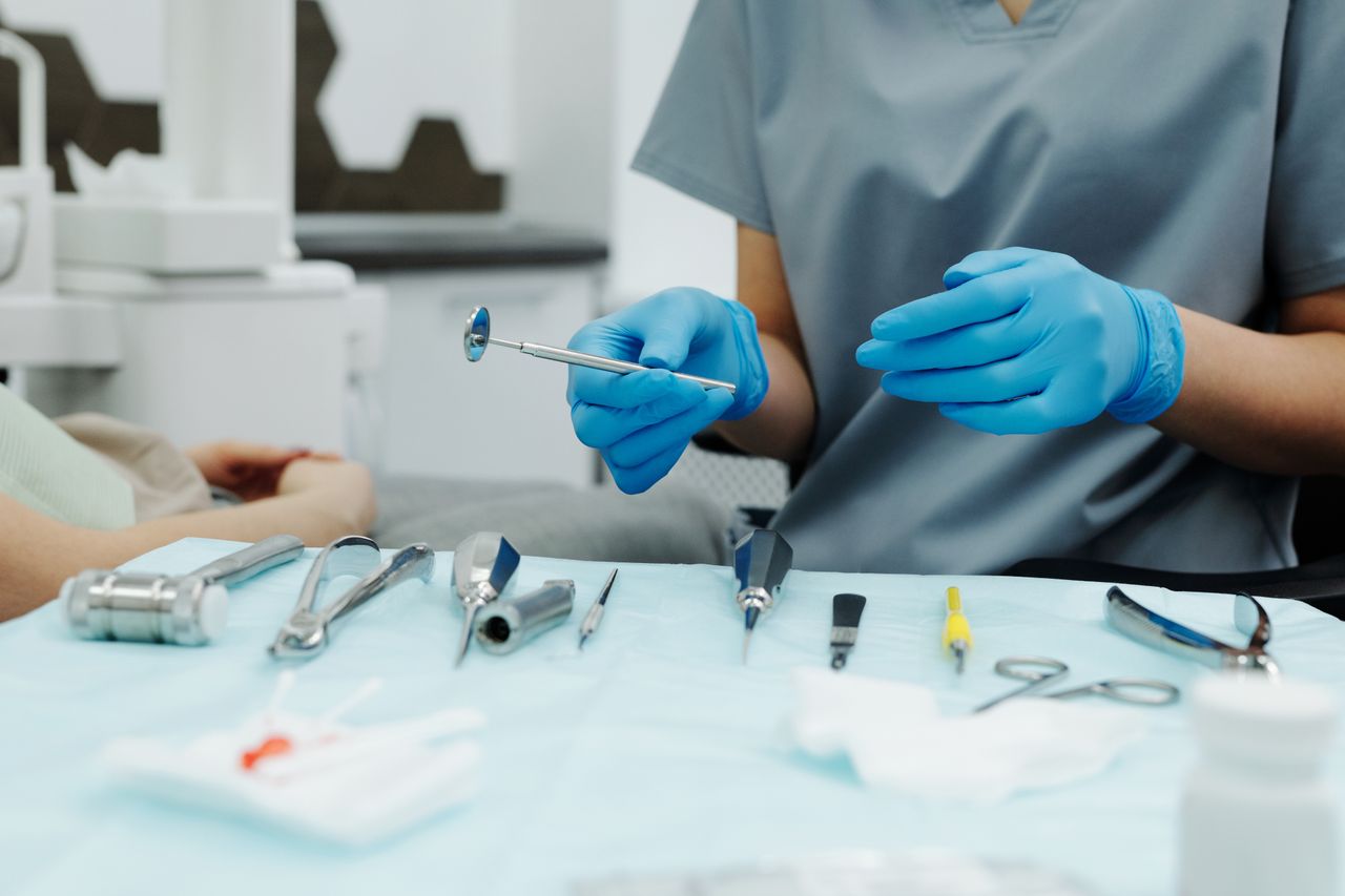 Dentist with gloves organizing instruments in a clinic setting, ready for a dental procedure.